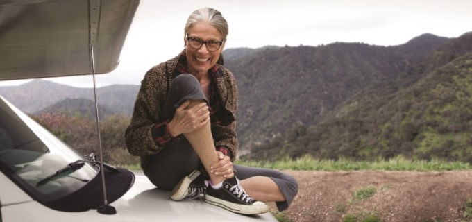 Woman sitting on mobile RV hood on adventure